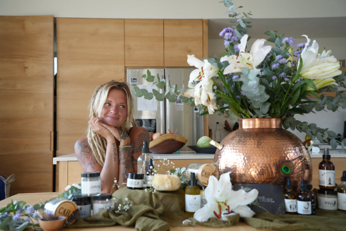 Woman in a kitchen with a copper vase and flowers on the counter
