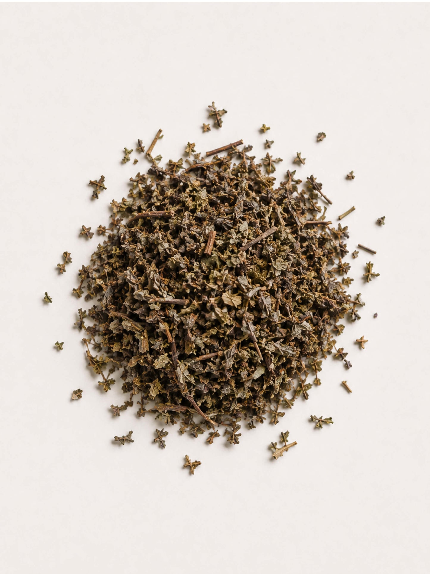 A small pile of Damiana dried green-brown herbs or tea leaves scattered on a plain off-white background.