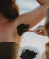 Applying Underarm Detox Mask clay paste to underarm area to remove heavy metals, rebalance microbiome, and reduce irritation naturally